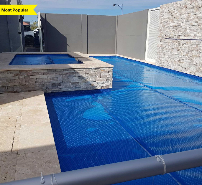 Daisy Solar Pool Cover 525B in blue, enhancing a stylish pool area with modern stone features.